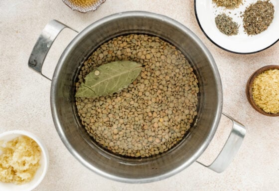 Lentils and a bay leaf in a pot covered with water.