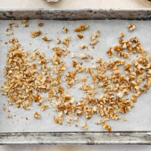 Walnuts spread across a baking sheet lined in parchment paper.