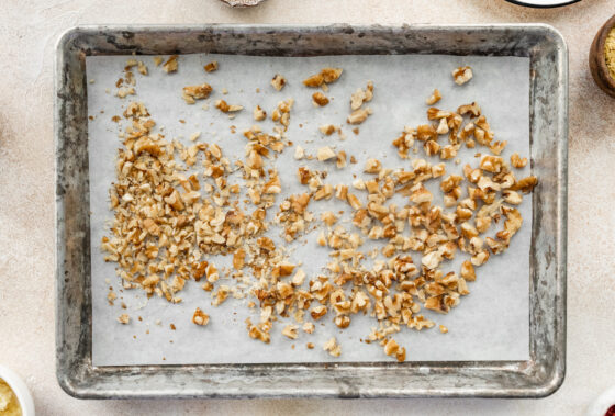 Walnuts spread across a baking sheet lined in parchment paper.