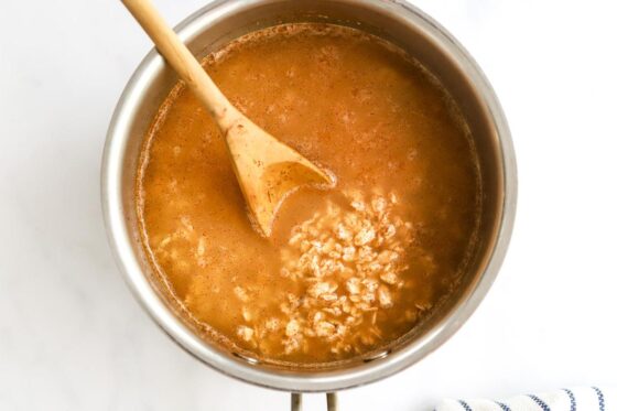 Oatmeal ingredients in a pot with a wooden spoon.