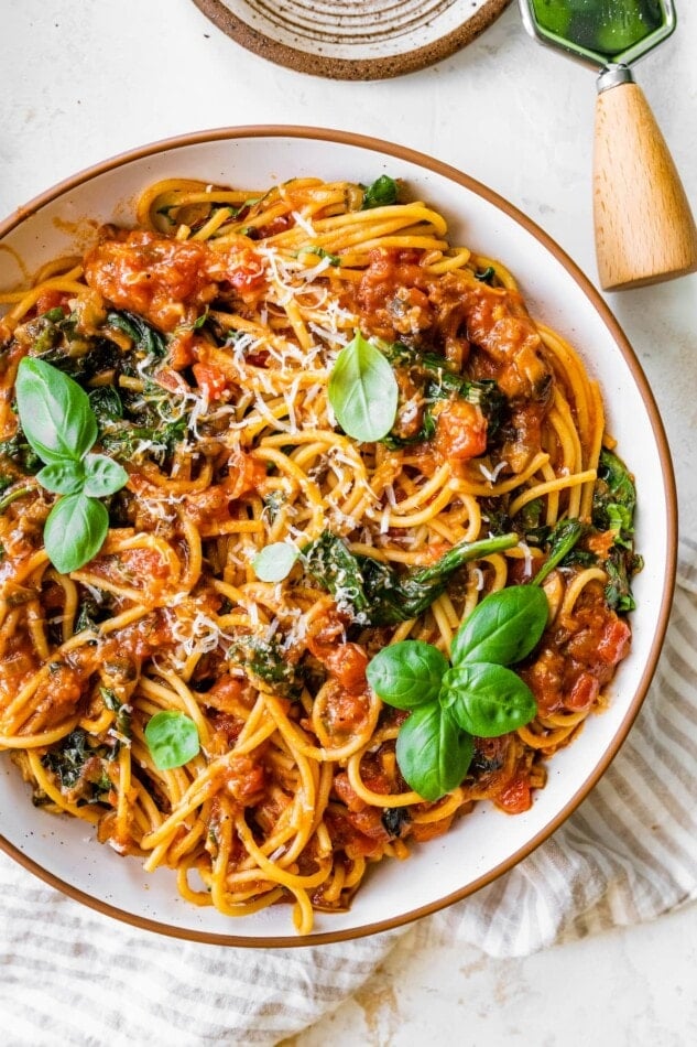 A bowl of pasta topped with fresh basil leaves.