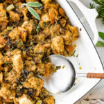 Sourdough stuffing in a serving dish with a serving spoon.