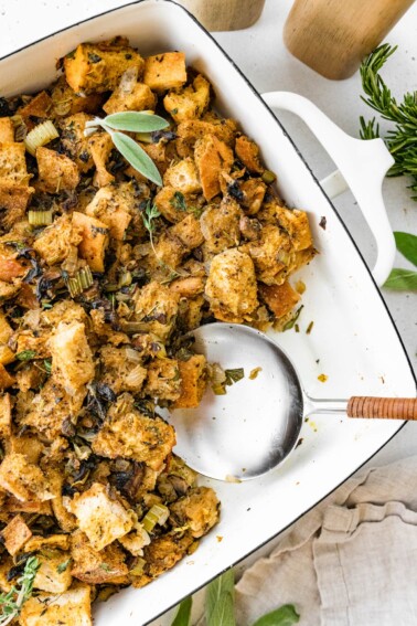 Sourdough stuffing in a serving dish with a serving spoon.