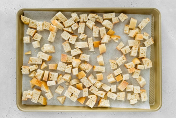 Sourdough cubes on a baking sheet lined with parchment paper.