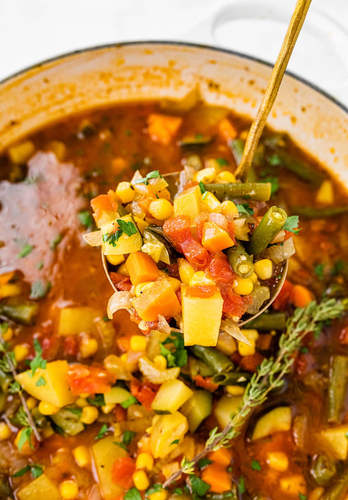 A serving spoonful of vegetable soup over a pot.