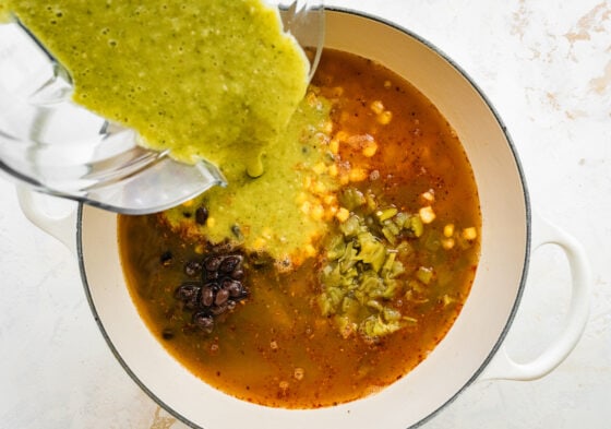 Pouring in chili verde mixture into sauce pan.