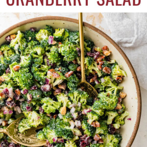 A serving bowl of broccoli cranberry salad with serving spoons.