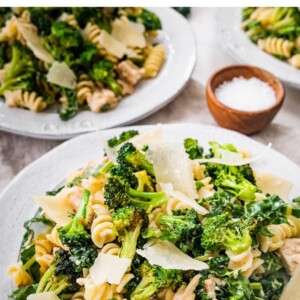 Tuna, broccoli and kale caesar pasta salad on a plate topped with shaved parmesan.