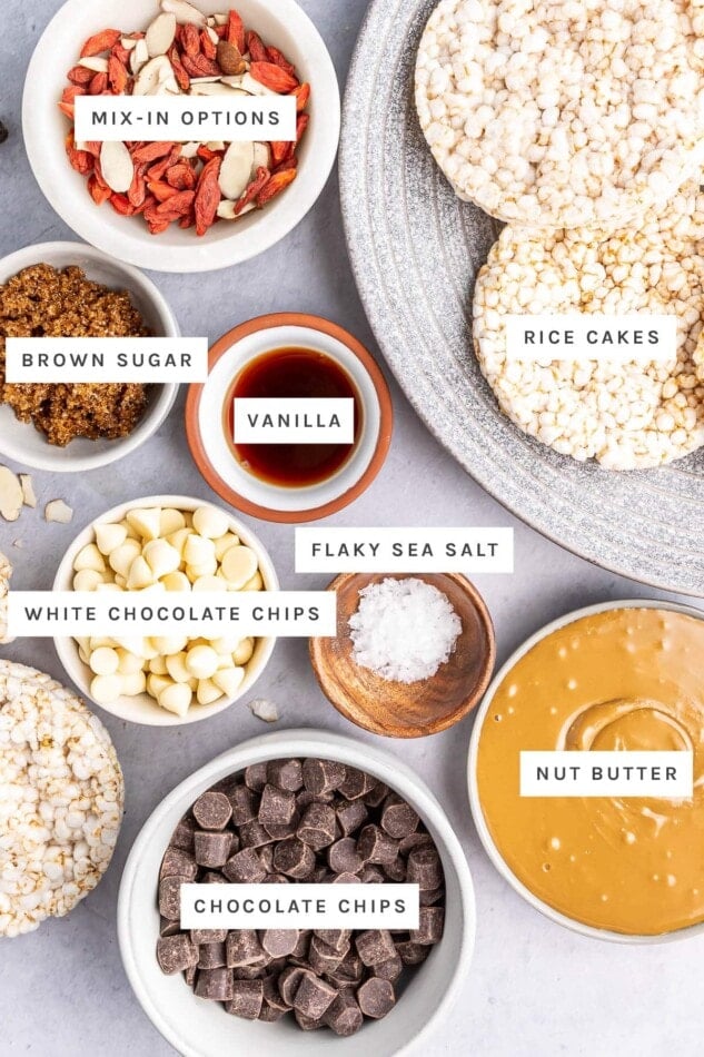 Ingredients measured out to make Crispy Chocolate Rice Cake Bars: mix-ins like fruit and nuts, rice cakes, brown sugar, vanilla, sea salt, white chocolate chips, nut butter and chocolate chips.