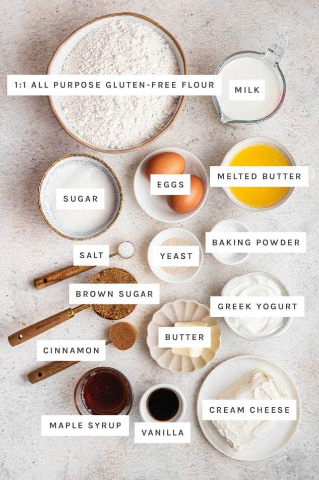 Ingredients measured out to make Gluten-Free Cinnamon Rolls: 1:1 all purpose gluten-free flour, milk, sugar, eggs, melted butter, salt, yeast, baking powder, brown sugar, Greek yogurt, butter, cinnamon, maple syrup, vanilla and cream cheese.
