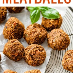 Vegan lentil meatballs with fresh basil on a cooling rack lined with parchment paper.