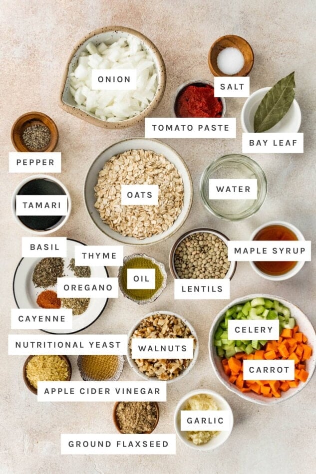 Ingredients measured out to make Lentil Meatballs: onion, salt, tomato paste, bay leaf, pepper, oats, tamari, water, basil, thyme, oregano, cayenne, oil, lentils, maple syrup, nutritional yeast, walnuts, celery, carrots, apple cider vinegar, ground flaxseed and garlic.