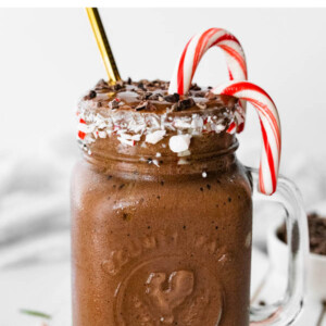 A chocolate peppermint smoothie next to a small candy dish with peppermints.