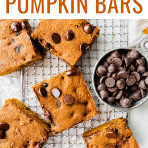 Chocolate chip pumpkin bars on a cooling rack. Cup of chocolate chips is next to the bars.