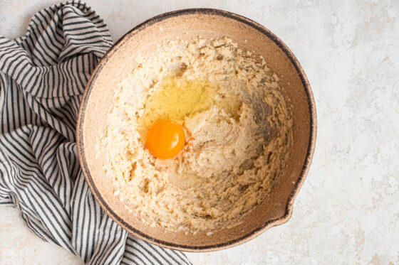 Cookie dough in a bowl with an egg added to it.