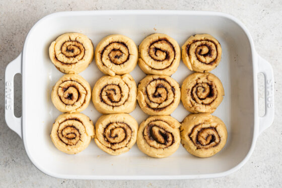 Cinnamon rolls placed 3 by 4 in a baking dish.