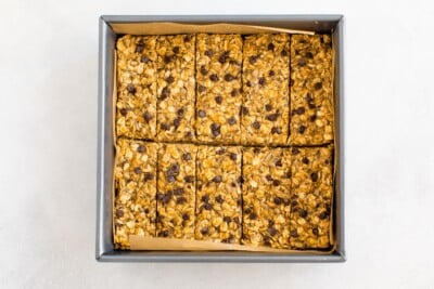Granola mixture cut into 10 bars in a square baking pan lined with parchment paper.