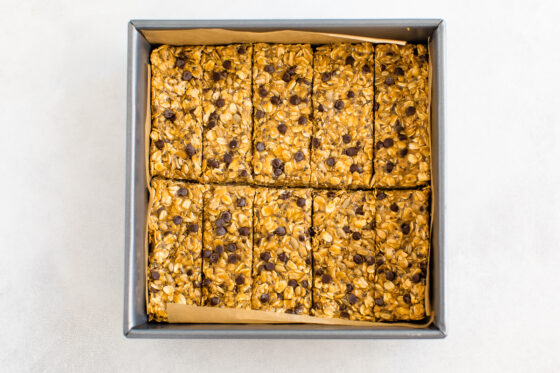 Granola mixture cut into 10 bars in a square baking pan lined with parchment paper.