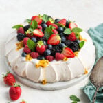 Pavlova topped with coconut whipped cream and fresh fruit.