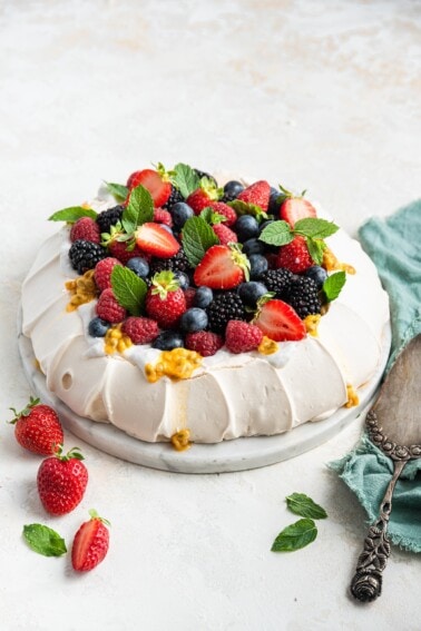 Pavlova topped with coconut whipped cream and fresh fruit.