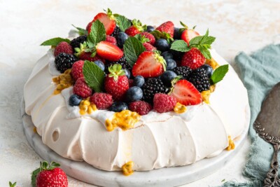 Pavlova topped with coconut whipped cream and fresh fruit.