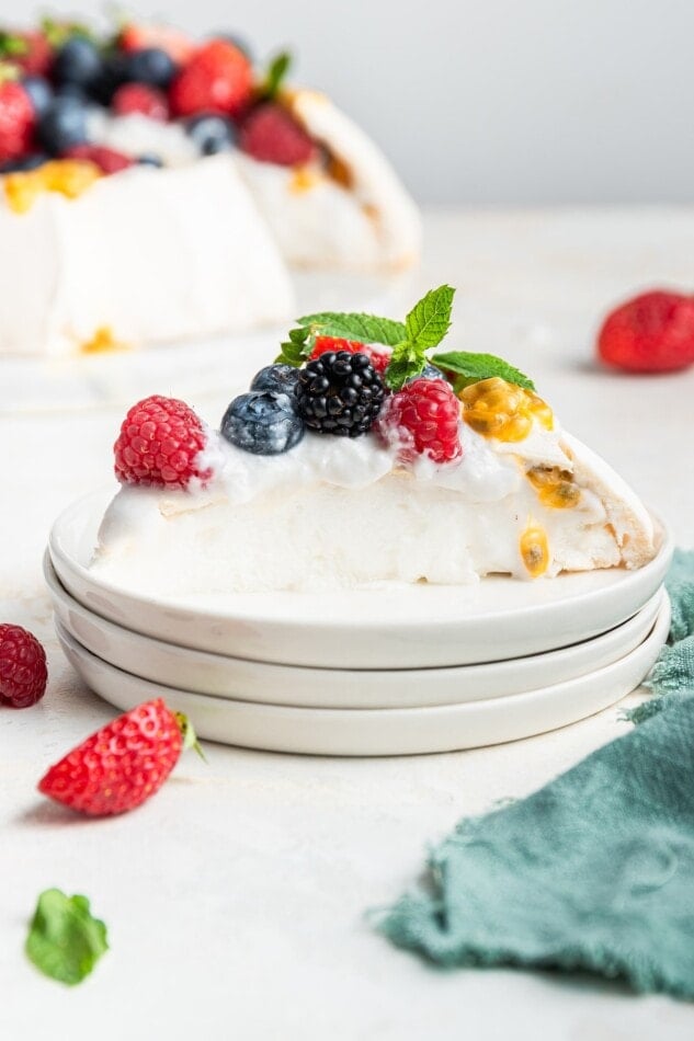 A slice of pavlova on some stacked plates.