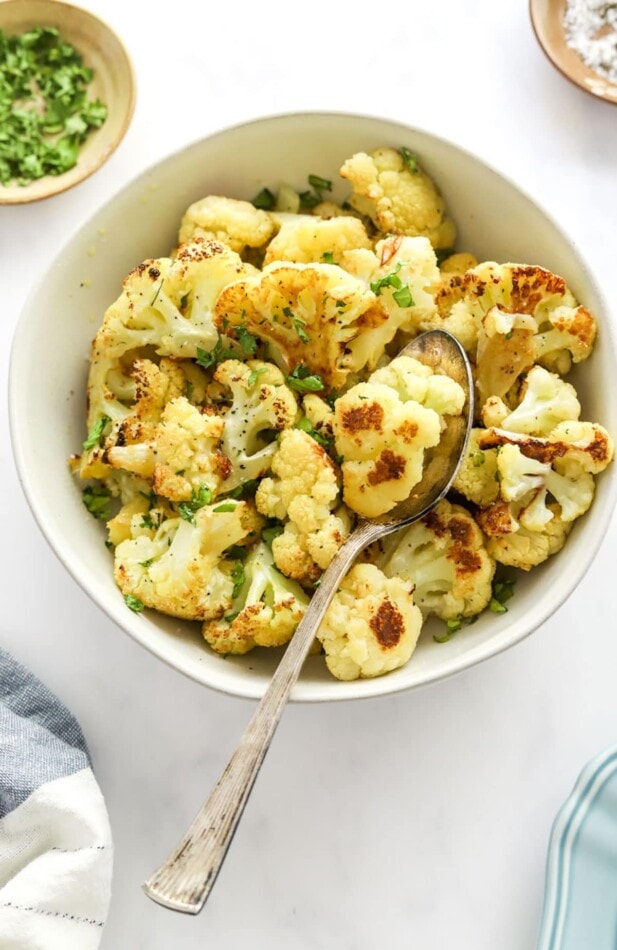 Roasted cauliflower in a bowl with a serving spoon.