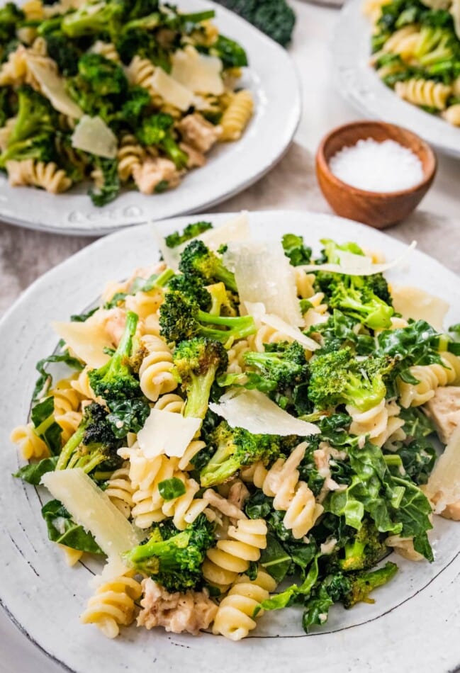 Tuna, broccoli and kale caesar pasta salad on a plate topped with shaved parmesan.