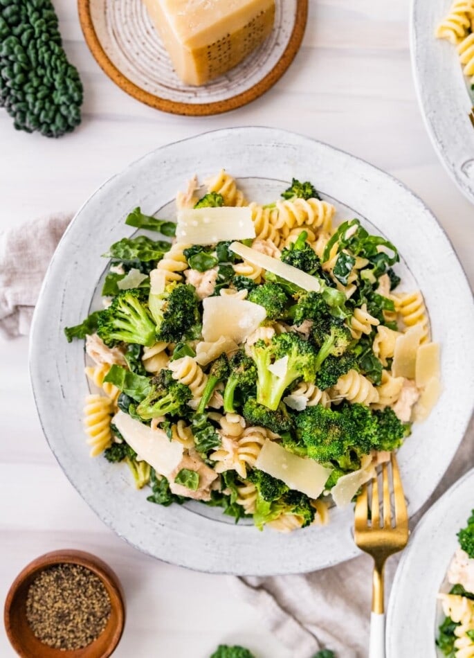 Tuna, broccoli and kale caesar pasta salad on a plate topped with shaved parmesan.