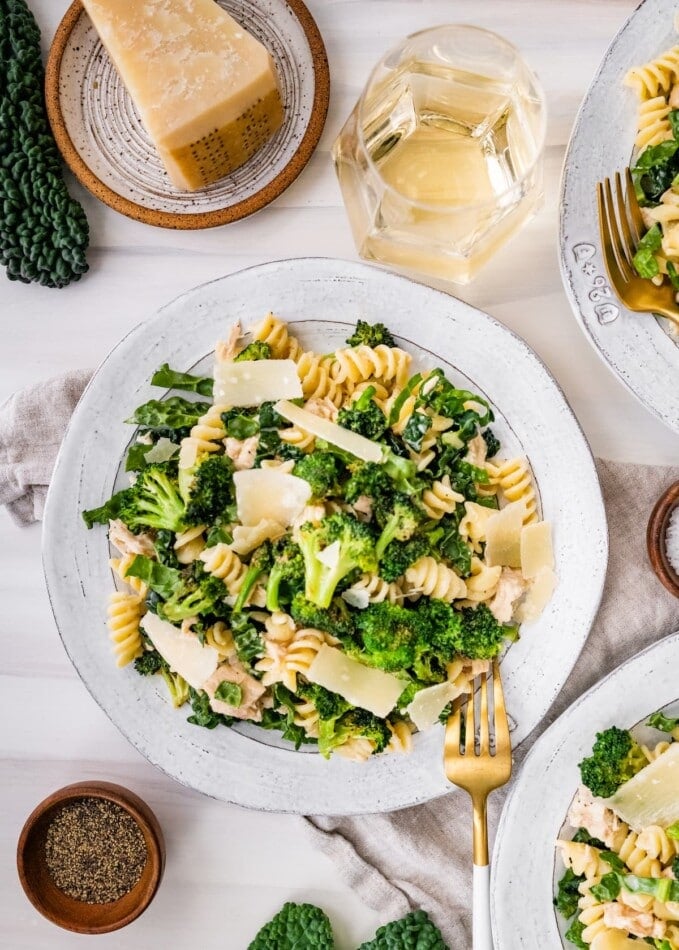 Tuna, broccoli and kale caesar pasta salad on a plate topped with shaved parmesan.