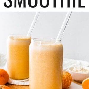 Two glasses of clementine smoothies with glass straws.