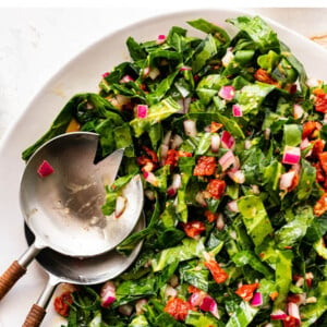 Collard green salad on a plate with serving spoons.