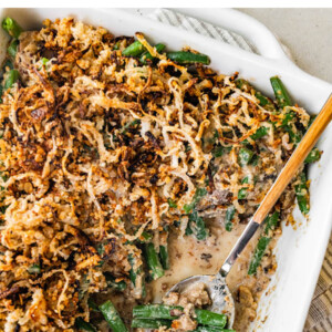 Homemade healthy green bean casserole in a square dish. A scoop is taken out with a spoon.