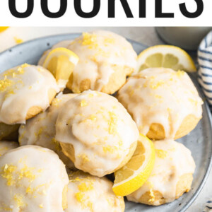 Lemon ricotta cookies on a plate with lemon wedges.