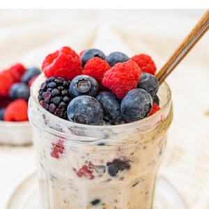 A jar of low calorie overnight oats topped with fresh mixed berries.