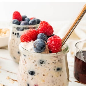A jar of low calorie overnight oats topped with fresh mixed berries.