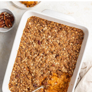 Healthy sweet potato casserole in a baking dish with a spoon.