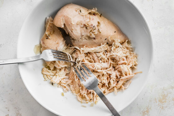 Shredding chicken in a bowl.