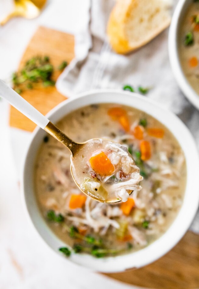 A spoonful of soup over a bowl.