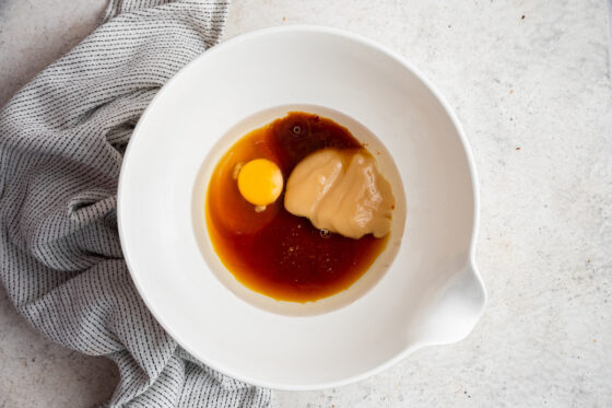 Egg, coconut oil, applesauce, maple syrup and vanilla extract in a bowl.