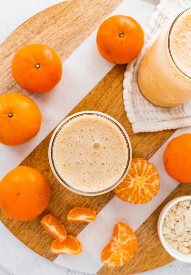 A clementine smoothie surrounded by clementines.