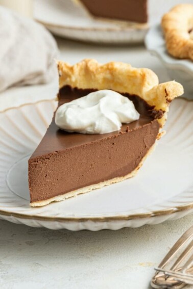 A slice of vegan chocolate pie with whipped topping on a plate.