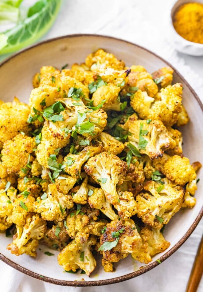 Curried cauliflower roasted to perfection with coconut oil, curry powder, garam masala and fennel seeds. It’s easy to whip up, amazingly flavorful and one of my all-time favorite vegetable side dishes. Curry roasted cauliflower in a bowl.