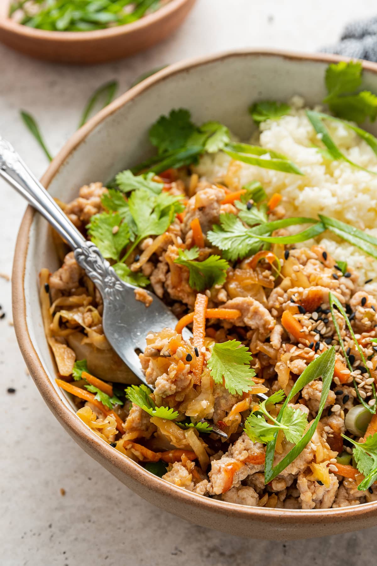 Egg roll in a bowl served with rice. A fork is scooping a bite.