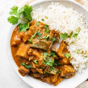 A shallow bowl of eggplant curry with rice.