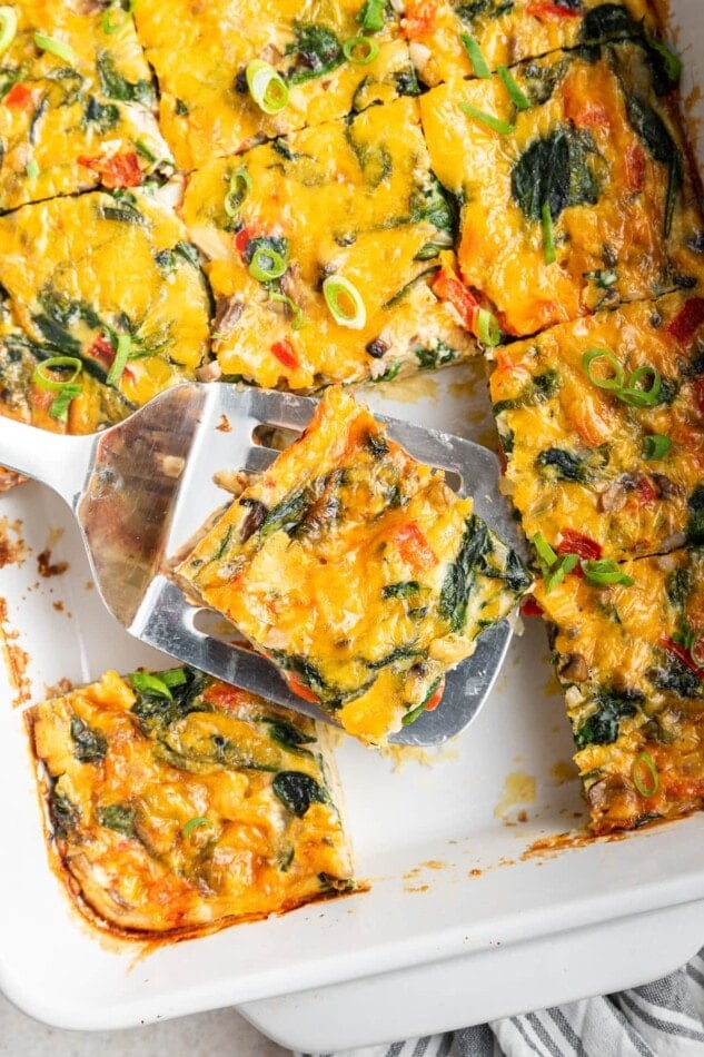 A spatula with a serving of casserole over a baking dish.