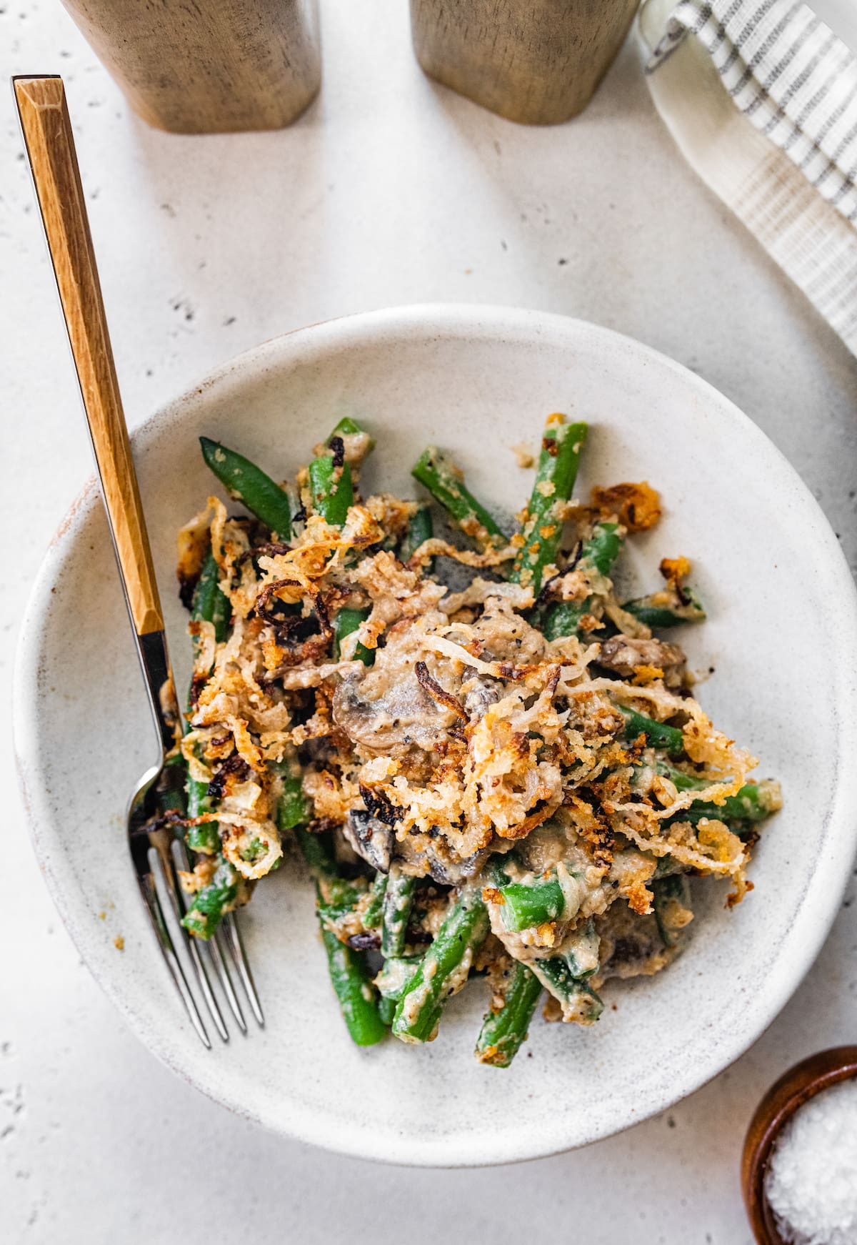 A serving of green bean casserole on a plate with a fork.