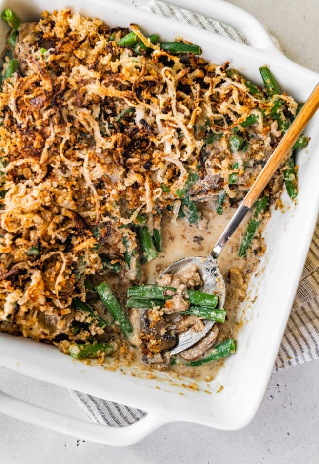 Healthy green bean casserole in a baking dish with a serving spoon.