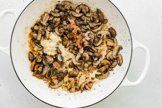 Mushrooms and seasonings in a sauté pan cooking.