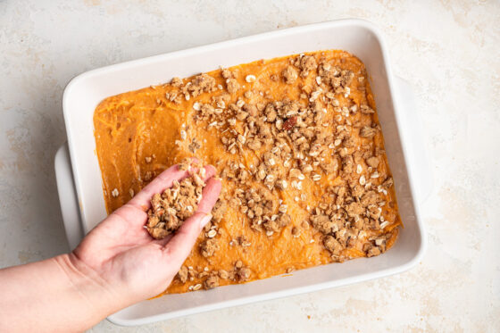 Topping the sweet potato mixture with the oatmeal topping.